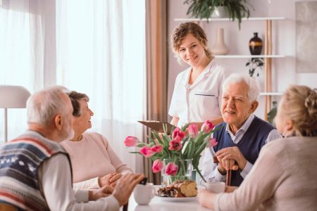 Elderly pensioners at retirement home talking during an afternoon snack